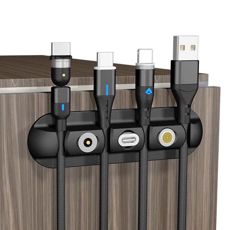 Black desktop charging magnetic data cable organizer on wooden surface